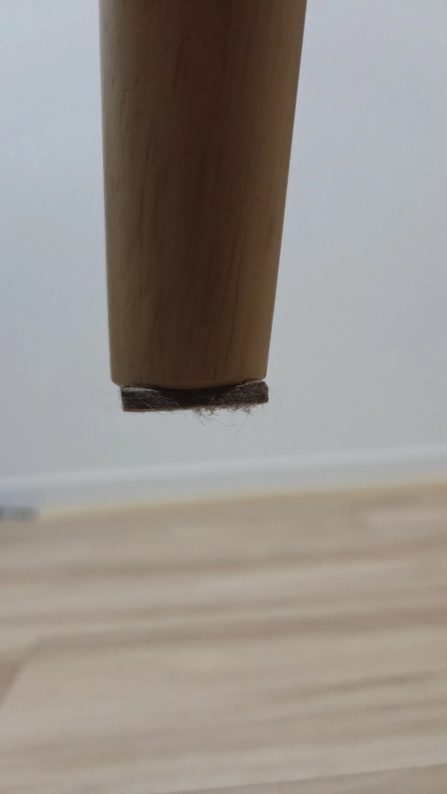木製の椅子脚先端からはみ出した茶色いフェルト状素材